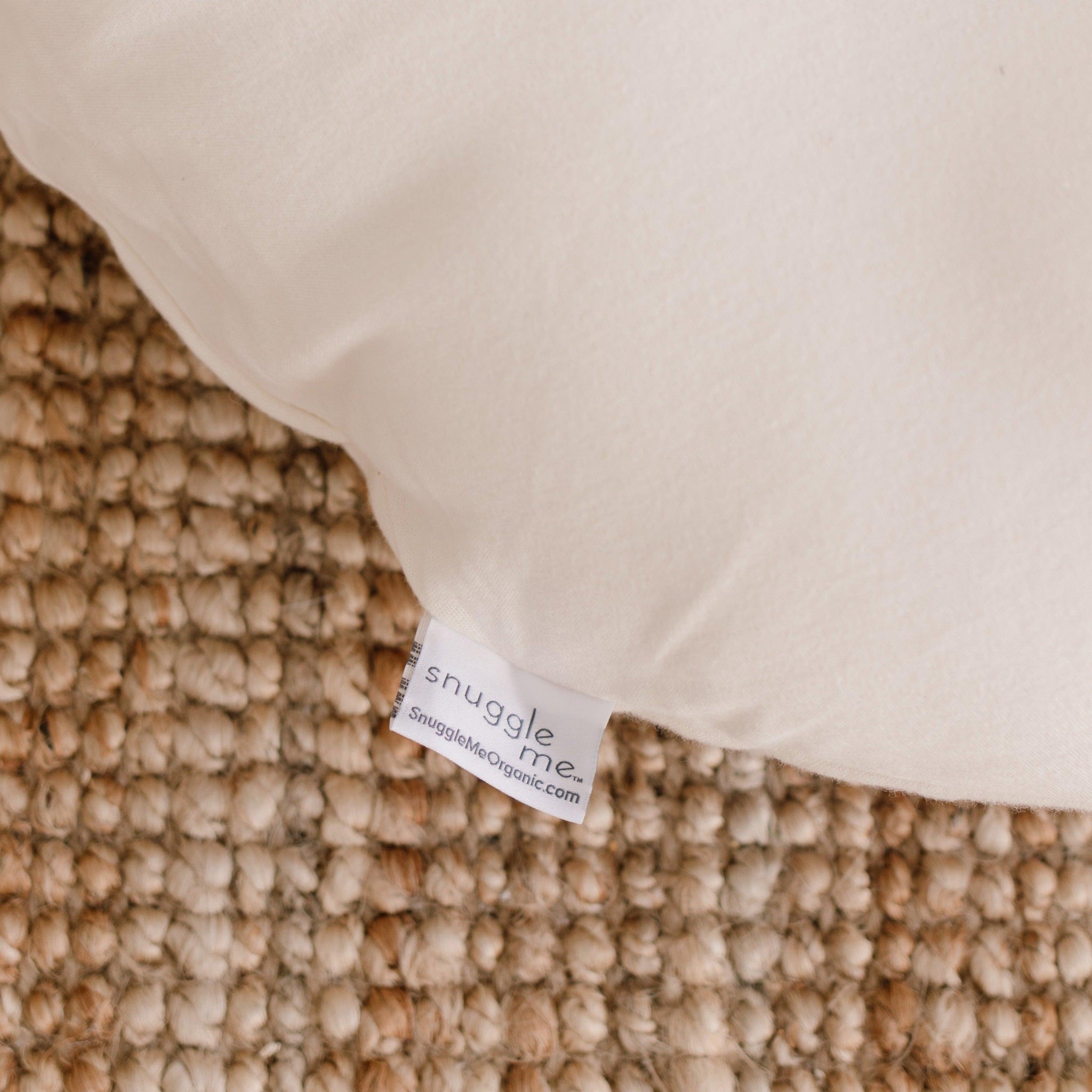 A close up image of The Snuggle Me® Lounger on a woven rug.