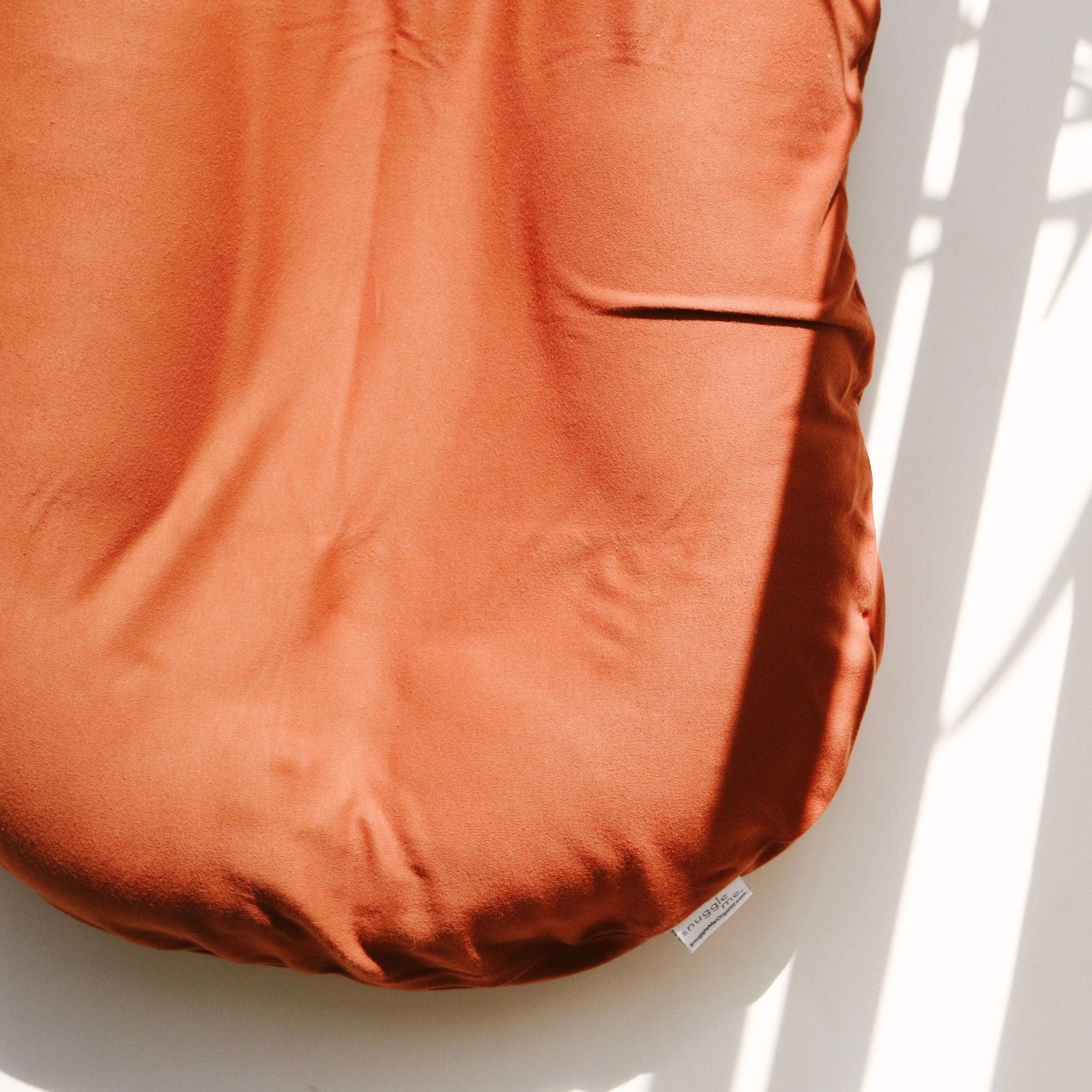 A close up image of The Snuggle Me® Lounger in a orange shade.